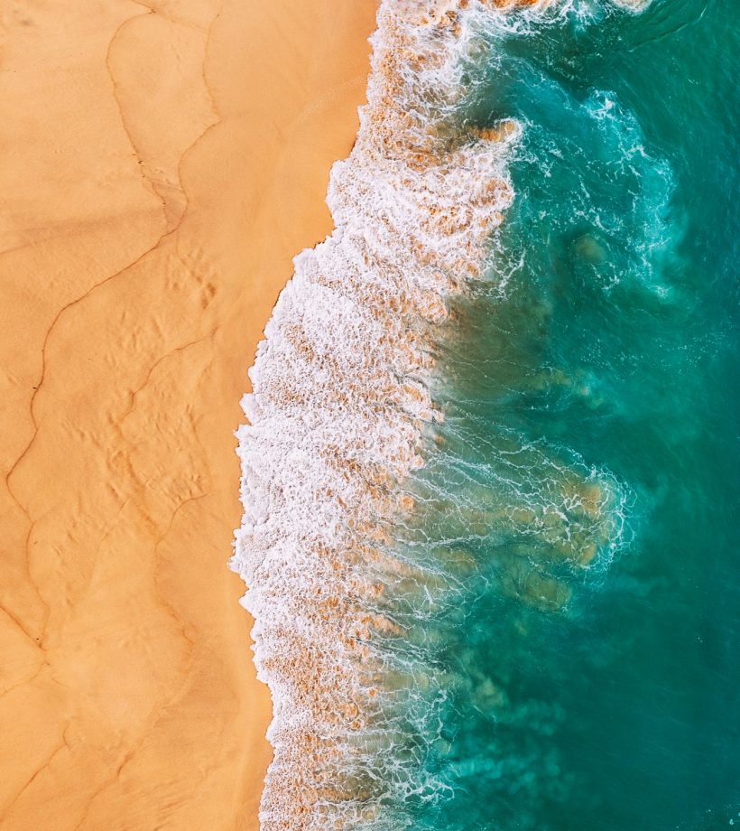Aerial view of the turquoise ocean waves on the beach. Beaches In Australia